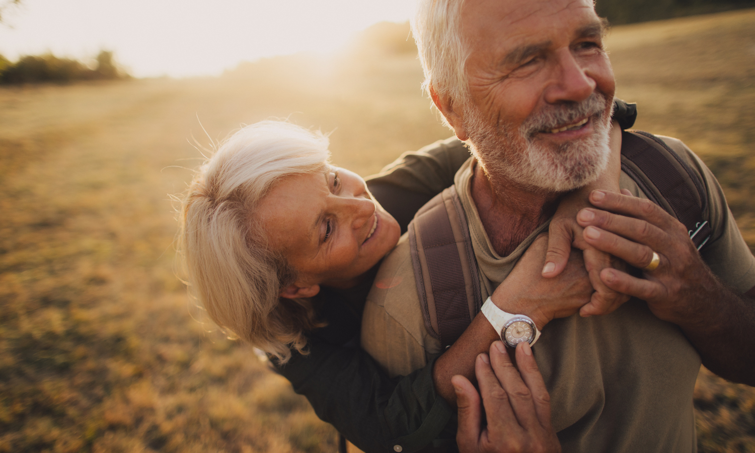 A happy retired couple embrace in a golden field