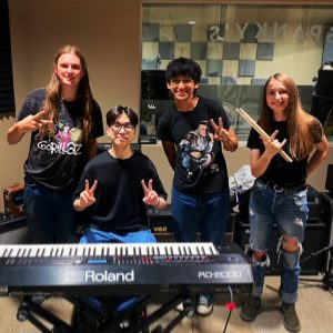 Four teens at the Alice Cooper Solid Rock Teen Center pose behind an electric piano.